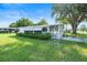 Charming single-story home featuring an awning, lush landscaping, and a well-maintained lawn under a sunny sky at 8973 Sw 103Rd Ln, Ocala, FL 34481