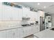Bright kitchen with stainless appliances, white cabinets, gray counters, tile backsplash, and decorative items above the cabinets at 9577 Sw 82Nd Street Rd, Ocala, FL 34481