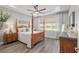 Spacious main bedroom with a four-poster bed, tray ceiling, and view of the green outdoors at 9577 Sw 82Nd Street Rd, Ocala, FL 34481