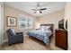 This cozy bedroom features wood-look tile, a ceiling fan, and a large window at 10451 Sw 98Th Place Rd, Ocala, FL 34481