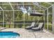 Relaxing poolside with chairs and umbrella on brick pavers under a screened enclosure, overlooking the lush yard at 1107 Se 49Th Ave, Ocala, FL 34471