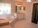Bright bathroom featuring a soaking tub, dual vanities, and tile flooring at 14561 Sw 112Th Cir, Dunnellon, FL 34432