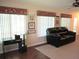 Relaxing living room featuring a comfortable couch, desk and vertical blinds at 14561 Sw 112Th Cir, Dunnellon, FL 34432