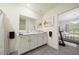 Bright bathroom featuring double sinks, white cabinetry, and a large mirror reflecting a bedroom at 160 Hickory Course Loop, Ocala, FL 34472