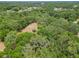 Sweeping aerial view of a densely wooded area, with a small clearing featuring a fire pit at 2580 Se 157Th Lane Rd, Summerfield, FL 34491