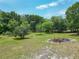 Lush backyard with mature trees and a fire pit, perfect for gathering and enjoying the outdoors at 2580 Se 157Th Lane Rd, Summerfield, FL 34491