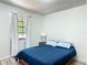 Bedroom with a plush blue bed, hardwood floors, a bedside table with lamp, and a window with white curtains at 2580 Se 157Th Lane Rd, Summerfield, FL 34491