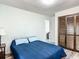 Bedroom with wood-look floors, closet with louvered doors, and blue bedding at 2580 Se 157Th Lane Rd, Summerfield, FL 34491
