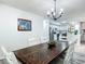 Open dining area with a rustic table set, a modern chandelier, and an opening to a white-cabinet kitchen at 2580 Se 157Th Lane Rd, Summerfield, FL 34491
