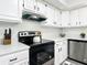 The kitchen features stainless steel appliances, white cabinets, quartz countertops, and dark hardware accents at 2580 Se 157Th Lane Rd, Summerfield, FL 34491