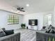 Bright living room features hardwood floors, a ceiling fan, large window, and a large television at 2580 Se 157Th Lane Rd, Summerfield, FL 34491
