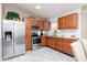Modern kitchen with wood cabinets, stainless steel appliances, and gray tile flooring at 340 Oak Track Loop, Ocala, FL 34472