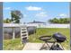 A backyard featuring a swimming pool with ladder, a white fence, green grass, and grill at 3887 Sw 156Th Pl, Ocala, FL 34473