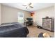 Comfortable bedroom with neutral tones, ceiling fan, window view, desk with computer, weights, and dresser at 3887 Sw 156Th Pl, Ocala, FL 34473