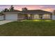 Charming single-story home with a well-manicured lawn and a two-car garage at sunset at 3887 Sw 156Th Pl, Ocala, FL 34473
