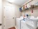 Bright laundry room with washer, dryer, storage shelf, door and fixtures at 3887 Sw 156Th Pl, Ocala, FL 34473