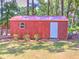 A charming red shed featuring a red roof, window with dark shutters, and a pristine white door at 5410 Nw 62Nd Ave, Ocala, FL 34482