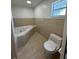 Bathroom with tiled walls, tiled flooring, a soaking tub, and a toilet at 5525 Se 43Rd Ct, Ocala, FL 34480