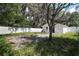 Backyard featuring a white vinyl fence, concrete pad, and mature trees, creating a private outdoor space at 719 Nw 8Th St, Ocala, FL 34475