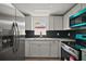 Bright kitchen featuring stainless steel refrigerator, light gray cabinets, black tile backsplash and granite countertops at 719 Nw 8Th St, Ocala, FL 34475