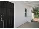Close-up of the black front door, white textured wall, and small window on the porch area at 719 Nw 8Th St, Ocala, FL 34475