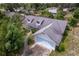 Aerial view of a single-Gathering home with a two-car garage, mature trees and shrubbery and a gray shingle roof at 8 Juniper Pass Way, Ocala, FL 34480