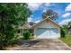 Charming single-Gathering home featuring a light yellow exterior, light blue trim and a two-car garage with a concrete driveway at 8 Juniper Pass Way, Ocala, FL 34480