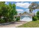 Charming single-Gathering home featuring a light yellow exterior, light blue trim and a two-car garage with a concrete driveway at 8 Juniper Pass Way, Ocala, FL 34480