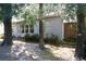 Home exterior surrounded by mature trees and lush landscaping, with a glimpse of a sunroom, creating a serene setting at 8735 Sw 192Nd Court Rd, Dunnellon, FL 34432