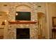 Cozy living room featuring a stone fireplace with a wooden mantel and a large TV, perfect for relaxing and entertaining at 8735 Sw 192Nd Court Rd, Dunnellon, FL 34432