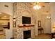 Cozy living room featuring a stone fireplace with a wooden mantel and a large TV at 8735 Sw 192Nd Court Rd, Dunnellon, FL 34432