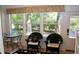 Bright sunroom with wicker chairs, small table, and a large window overlooking a lush green yard at 8735 Sw 192Nd Court Rd, Dunnellon, FL 34432
