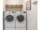 Modern laundry room with front-loading washer and dryer and overhead shelving for organized storage at 9658 Sw 76Th Lane Rd, Ocala, FL 34481