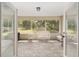 A screened-in porch features neutral flooring and white wicker furniture with a view of the yard at 1601 Ne 47Th Ct, Ocala, FL 34470