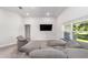 Comfortable living room with plush gray seating, a mounted TV, and natural light from the window at 181 Nw 45Th Loop, Ocala, FL 34475