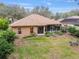 Back exterior view of a home showcasing a screened porch, lush backyard, and outdoor seating area at 19586 Sw 84Th Pl, Dunnellon, FL 34432