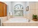 Bright bathroom features a large soaking tub beneath an arched window, creating a spa-like ambiance at 19586 Sw 84Th Pl, Dunnellon, FL 34432