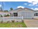 Charming single-story home with a well-manicured lawn and a white picket fence under a sunny blue sky at 2608 Botello Ave, The Villages, FL 32162