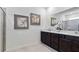 Bathroom with a dual sink vanity, granite countertop, framed mirrors, and tiled floors at 3066 Canopy Oak Blvd, Wildwood, FL 34785