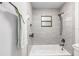 Bright bathroom features a tub with shower, light gray tile, and sleek dark fixtures at 4701 Nw 60Th Terrace, Ocala, FL 34482