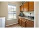 Well-equipped laundry room with wooden cabinets and granite countertops at 6235 Sw 95Th Pl, Ocala, FL 34476