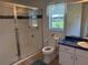 Bright bathroom featuring tiled shower, blue-toned vanity, and a window providing natural light and ventilation at 6925 Nw Highway 225A, Ocala, FL 34482
