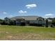 Charming single-story home showcasing manicured lawn, complemented by a bright blue sky with fluffy clouds at 6925 Nw Highway 225A, Ocala, FL 34482
