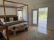 Main bedroom featuring a four-poster bed, wood floors, and access to the screened patio at 6925 Nw Highway 225A, Ocala, FL 34482