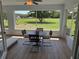 Enclosed patio area with table and chairs overlooking a lush green yard with mature tree at 6925 Nw Highway 225A, Ocala, FL 34482
