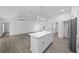 Open-concept kitchen featuring a large island, stainless steel refrigerator, and sleek gray flooring throughout the space at 7 Walnut Pl, Ocala, FL 34480