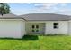 View of the home's white exterior from the green backyard and covered patio area at 8293 Se 158Th St, Summerfield, FL 34491