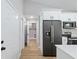 Hallway featuring a laundry area view, a modern stainless refrigerator, and white cabinetry at 8293 Se 158Th St, Summerfield, FL 34491