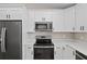 Bright kitchen features white cabinets, stainless steel appliances and quartz countertops at 8293 Se 158Th St, Summerfield, FL 34491