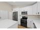 Modern kitchen features an island, white cabinets, stainless steel appliances, and quartz countertops at 8293 Se 158Th St, Summerfield, FL 34491
